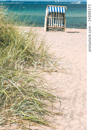 Sand dune with grass and blue colored roofed 34890373