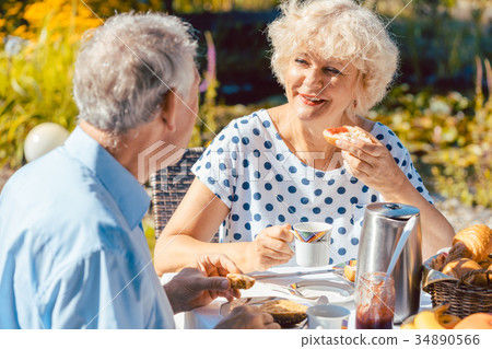 Happy elderly couple eating breakfast in their Happy elderly couple eating breakfast in their 34890566