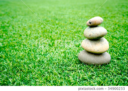 stones stacked up on grass 34900233
