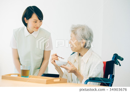 Senior woman and young carer eating 34903676