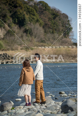 Rear view of a young couple on the riverbank Rear view of a young couple on the riverbank 34916887