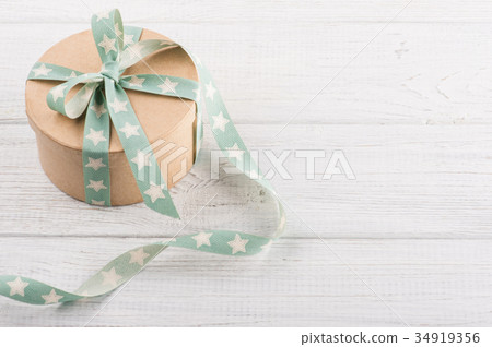 Gift box with star ribbon on white rustic table Gift box with star ribbon on white rustic table 34919356