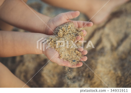 Child little hands holding sand close soft focus  34931911
