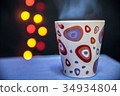 a mug of hot tea on the background of lights 34934804