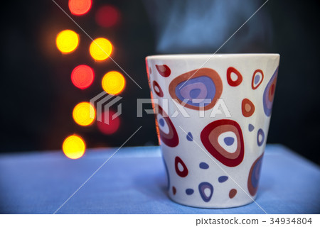 a mug of hot tea on the background of lights 34934804