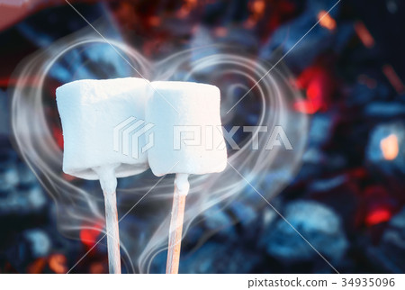 Two white sweet marshmallows roasting over fire Two white sweet marshmallows roasting over fire 34935096
