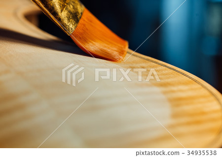 violin maker varnishing a violin body close up. violin maker varnishing a violin body close up. 34935538