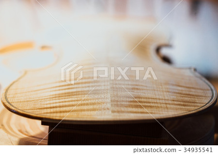 violin maker varnishing a violin body close up. 34935541