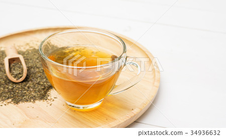 A cup of tea and a green tea leaf on a table. A cup of tea and a green tea leaf on a table. 34936632