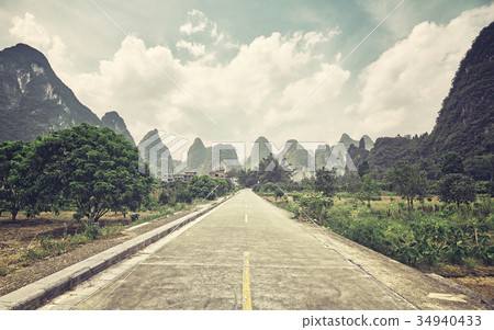 Retro stylized picture of a countryside road. 34940433