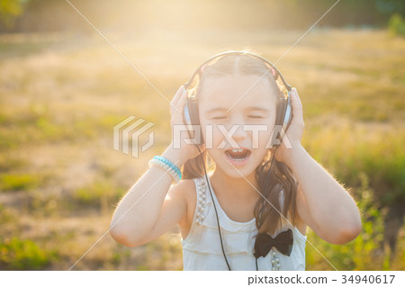 Little girl listening music with headphones 34940617