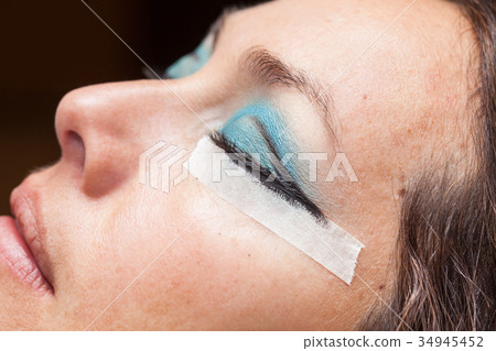 Woman while make up artist creates cat eyes Woman while make up artist creates cat eyes 34945452