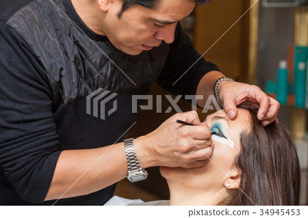 Make up artist creating cat eyes on a white woman Make up artist creating cat eyes on a white woman 34945453