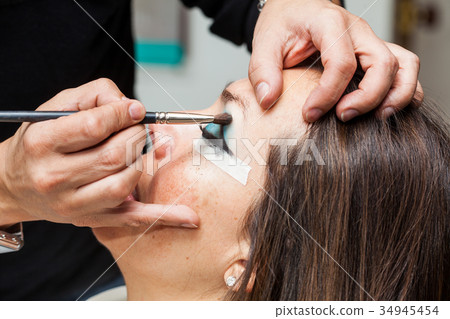 Make up artist creating cat eyes on a white woman Make up artist creating cat eyes on a white woman 34945454