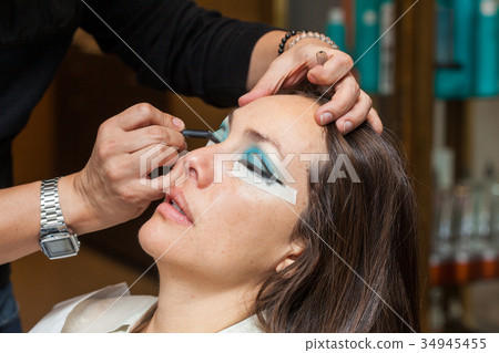 Make up artist creating cat eyes on a white woman 34945455
