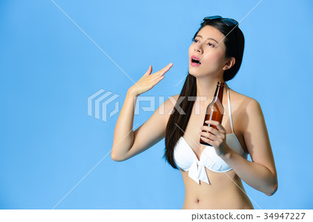 girl holding beer standing in blue background 34947227