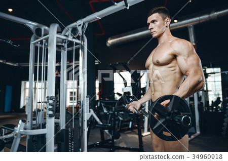 Handsome model young man training arms in gym 34960918