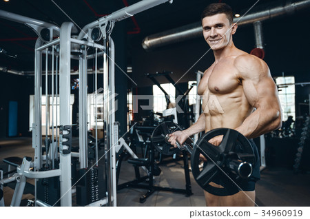Handsome model young man training arms in gym Handsome model young man training arms in gym 34960919