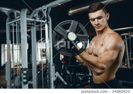 Handsome model young man training arms in gym 34960920
