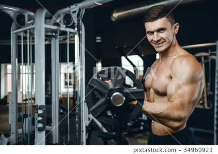 Handsome model young man training arms in gym Handsome model young man training arms in gym 34960921