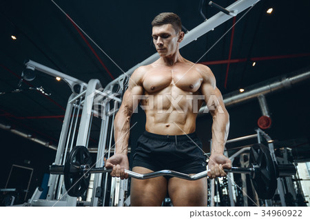 Handsome model young man training arms in gym Handsome model young man training arms in gym 34960922