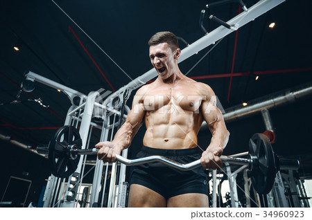Handsome model young man training arms in gym Handsome model young man training arms in gym 34960923