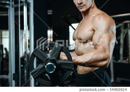 Handsome model young man training arms in gym Handsome model young man training arms in gym 34960924