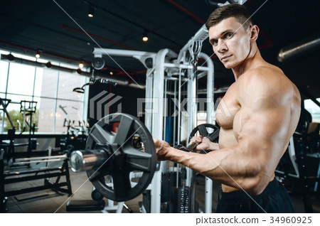 Handsome model young man training arms in gym 34960925