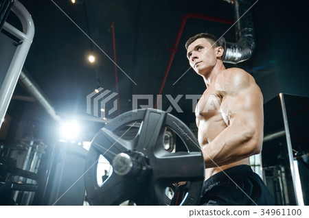 Handsome model young man training arms in gym Handsome model young man training arms in gym 34961100