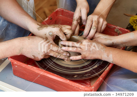Hands of three people create pot, potter's wheel 34971209