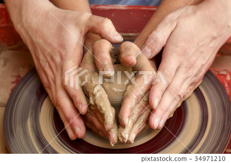 Hands of two people create pot, potter's wheel 34971210