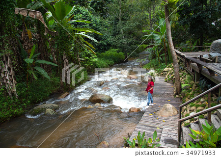 Woman tourism standing on little waterfall,stream Woman tourism standing on little waterfall,stream 34971933