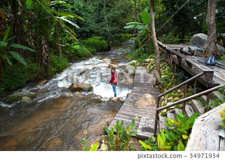 Woman tourism standing on little waterfall,stream Woman tourism standing on little waterfall,stream 34971934