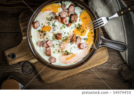 Tasty cooked egg with chopped sausages. 34974459