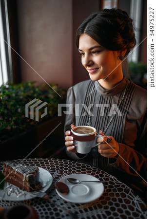 A young girl with a cup of coffee in retro cafe A young girl with a cup of coffee in retro cafe 34975227