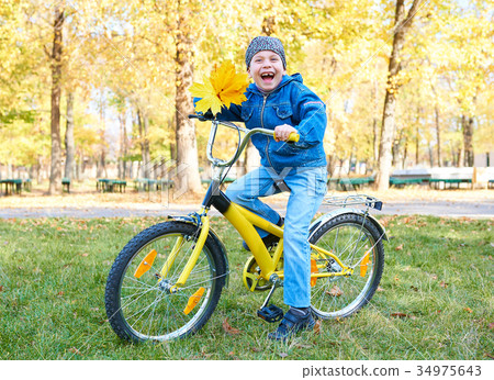 圖庫照片: boy riding on bicycle in autumn park