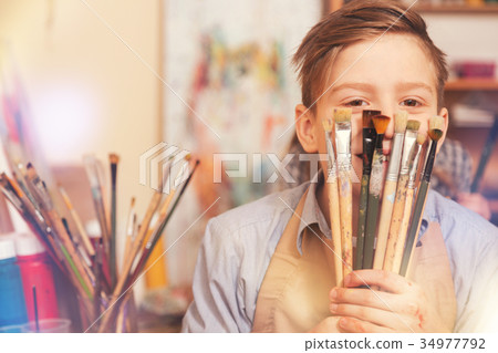 Funny teenage boy playing with brushes while Funny teenage boy playing with brushes while 34977792