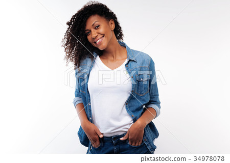 Charming curly woman holding hands in pockets of 34978078