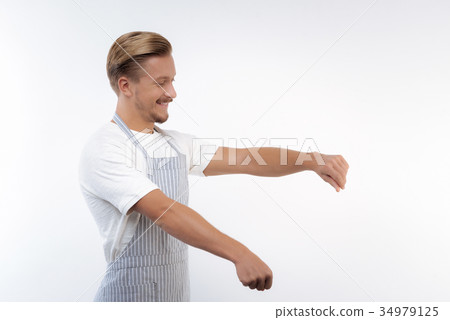 Smiling man in apron imitating cooking process Smiling man in apron imitating cooking process 34979125