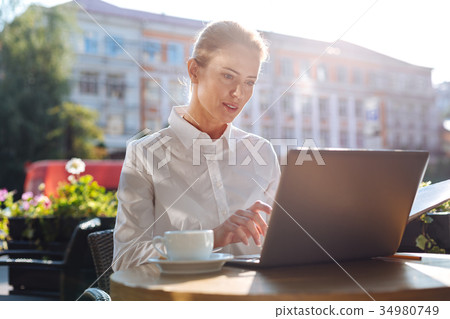 Beautiful businesswoman typing on laptop in cafe Beautiful businesswoman typing on laptop in cafe 34980749