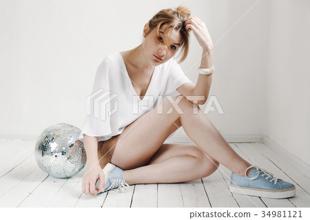 woman holding disco ball, posing white background 34981121