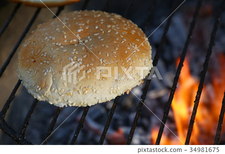 Close up sesame bun for burger on bbq fire grill Close up sesame bun for burger on bbq fire grill 34981675