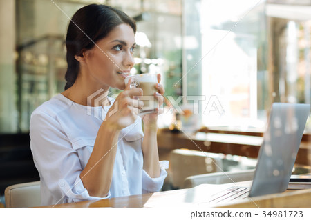 Charming dark-haired woman drinking latte in cafe Charming dark-haired woman drinking latte in cafe 34981723