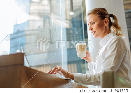 Inspired woman drinking latte and browsing web in 34981725