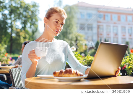Charming woman reading newsfeeds in cafe 34981909