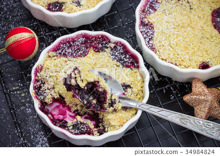 Homemade crumble with berries plum in ramekin 34984824