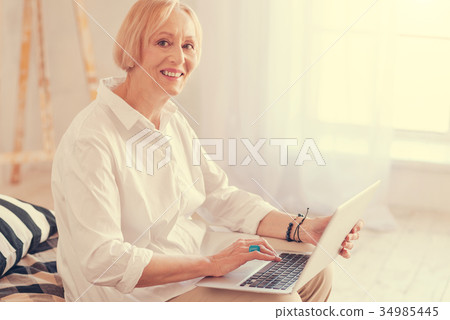 Cheerful aged woman using her laptop Cheerful aged woman using her laptop 34985445