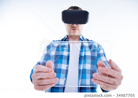 Serious young man holding a tablet in front of him 34987705