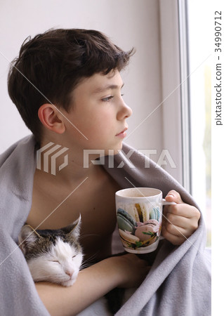 teenager boy drink hot cacao milk wrap in rug with cat teenager boy drink hot cacao milk wrap in rug with cat 34990712