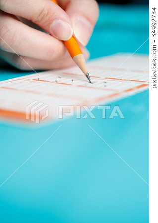 Photo of man marking with pencil in lottery ticket Photo of man marking with pencil in lottery ticket 34992734
